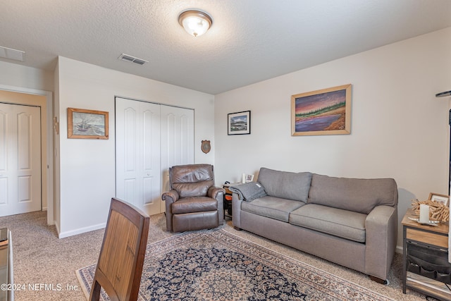 carpeted living room with visible vents, a textured ceiling, and baseboards