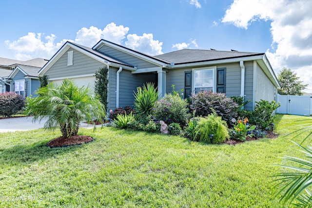 view of front of house with a front lawn, an attached garage, fence, and a gate