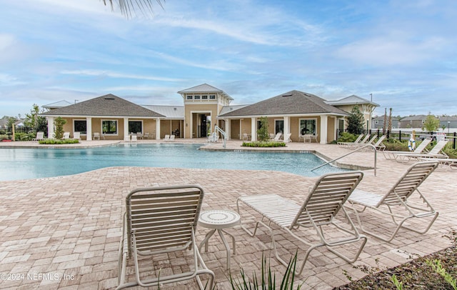 pool featuring a patio area, fence, an exterior structure, and an outdoor structure