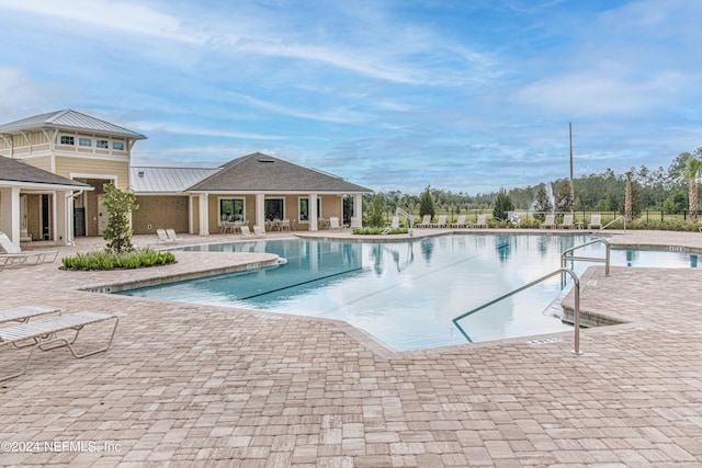 community pool with a patio area and fence