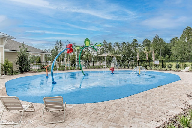 view of swimming pool featuring a water play area, fence, and a patio