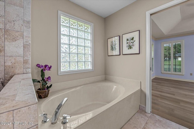 bathroom featuring tile patterned flooring, a bath, and baseboards