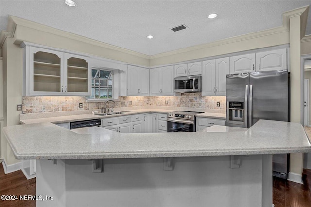 kitchen with glass insert cabinets, a breakfast bar area, ornamental molding, stainless steel appliances, and a sink