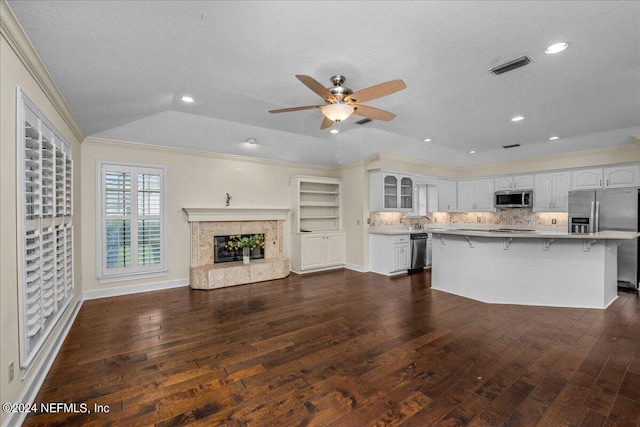 kitchen with a tile fireplace, visible vents, a kitchen breakfast bar, appliances with stainless steel finishes, and dark wood finished floors