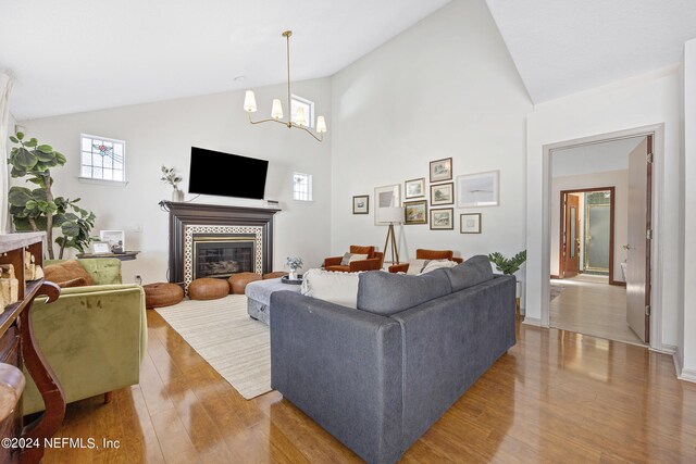 living room with light hardwood / wood-style flooring, a notable chandelier, and high vaulted ceiling