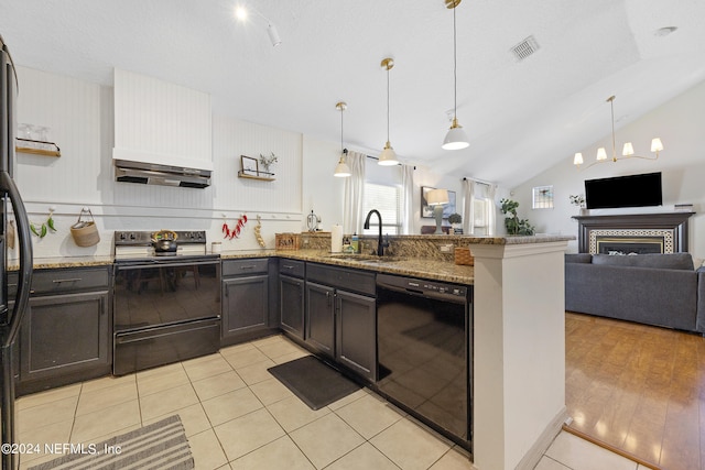 kitchen featuring lofted ceiling, hanging light fixtures, sink, black appliances, and dark stone countertops