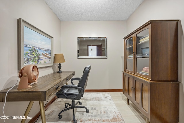 office space featuring a textured ceiling and light wood-type flooring