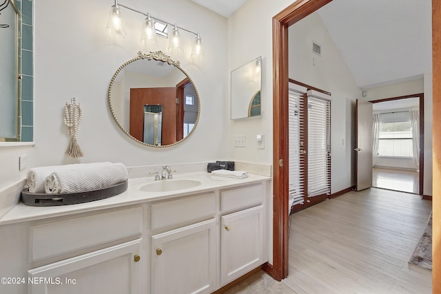 bathroom with wood-type flooring, lofted ceiling, and vanity