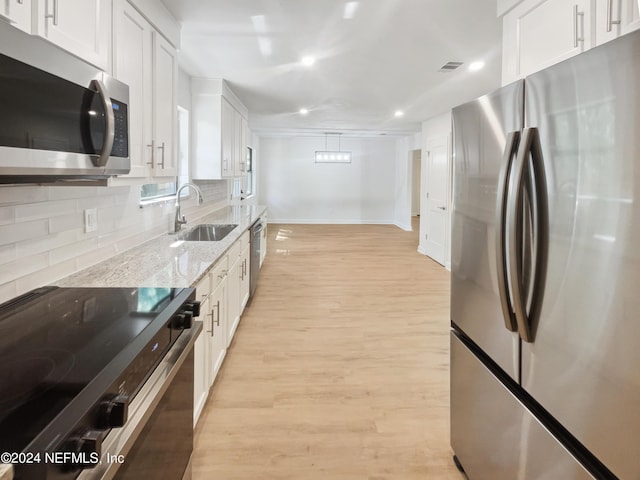 kitchen featuring light wood-style flooring, white cabinetry, stainless steel appliances, and a sink