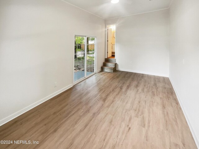 unfurnished room with ornamental molding, wood finished floors, and baseboards