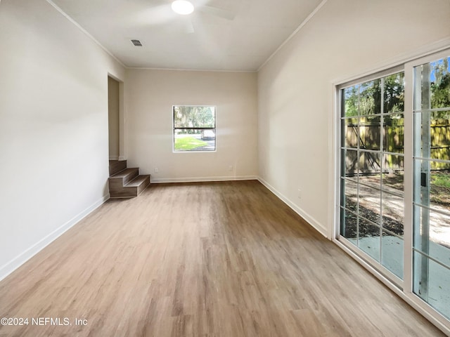 empty room with ornamental molding, visible vents, baseboards, and wood finished floors