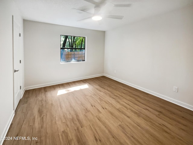 unfurnished room featuring ceiling fan, wood finished floors, and baseboards