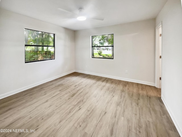 spare room featuring a ceiling fan, plenty of natural light, baseboards, and wood finished floors