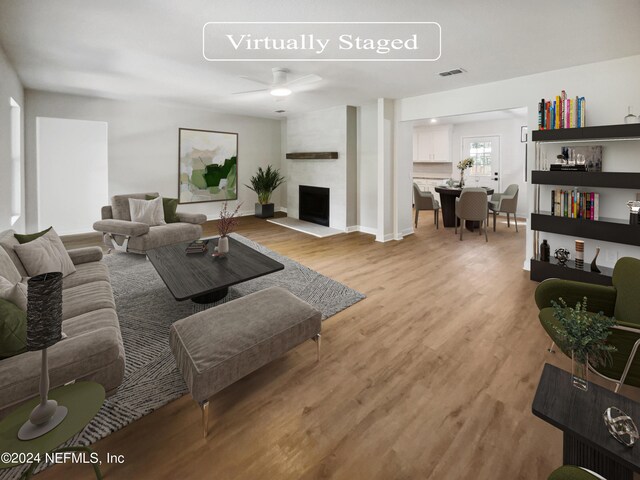 living room featuring ceiling fan, a fireplace, and light hardwood / wood-style floors