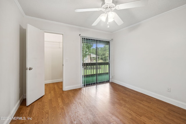 empty room with ornamental molding, a ceiling fan, baseboards, and wood finished floors