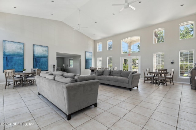 living area with ceiling fan, light tile patterned flooring, baseboards, vaulted ceiling, and french doors