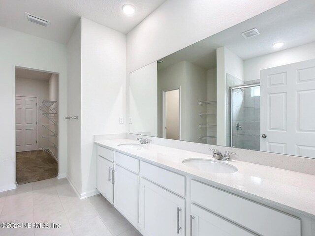 bathroom with tile patterned flooring, a textured ceiling, vanity, and walk in shower