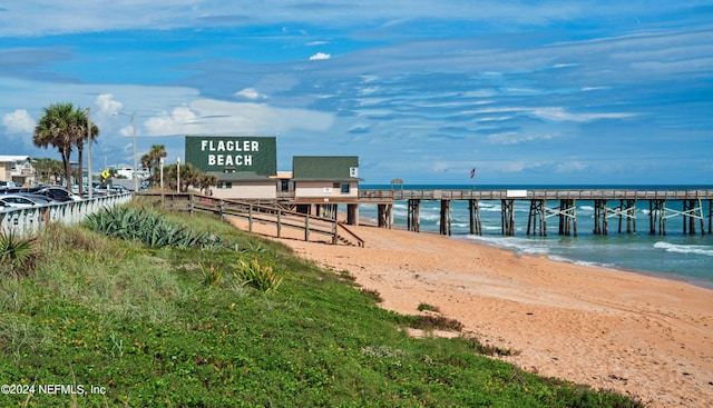 view of dock featuring a beach view and a water view