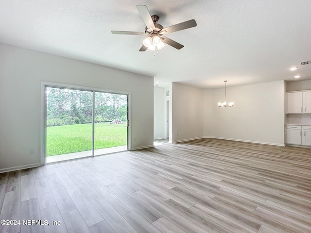 unfurnished living room with baseboards, light wood-style flooring, a textured ceiling, and ceiling fan with notable chandelier