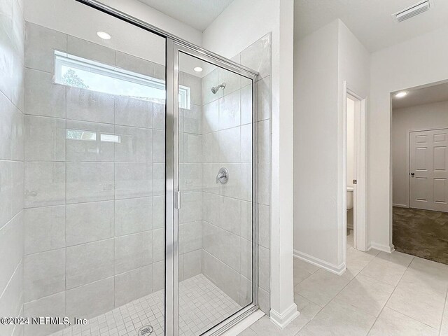 bathroom with toilet, walk in shower, and tile patterned flooring