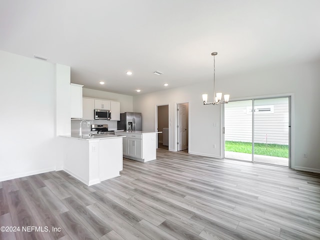 kitchen with light wood-type flooring, hanging light fixtures, white cabinets, sink, and stainless steel appliances