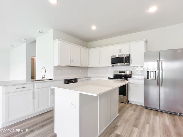 kitchen with appliances with stainless steel finishes, light hardwood / wood-style flooring, white cabinets, and sink