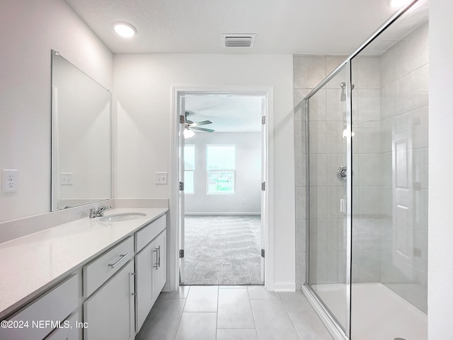 bathroom with tile patterned floors, a shower with door, vanity, and ceiling fan