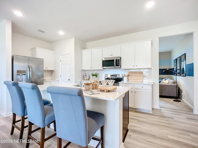 kitchen featuring white cabinetry, a center island with sink, appliances with stainless steel finishes, and light countertops