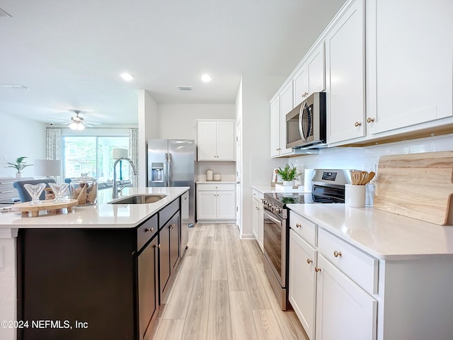 kitchen featuring stainless steel appliances, white cabinets, light countertops, and a sink