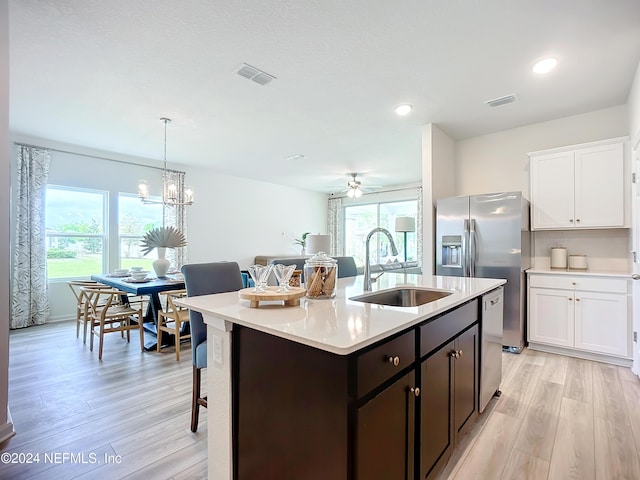 kitchen featuring stainless steel appliances, light countertops, hanging light fixtures, white cabinets, and a sink