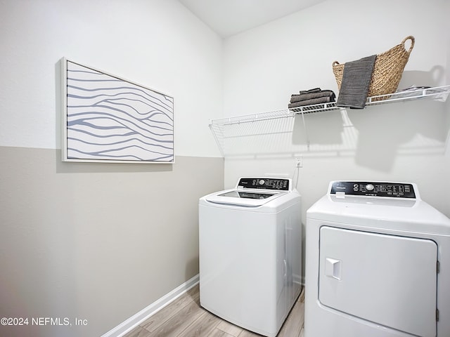 washroom with laundry area, washing machine and dryer, baseboards, and light wood-style flooring