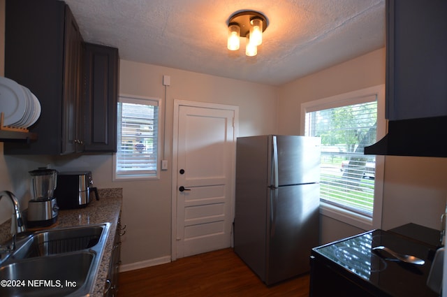 kitchen with sink, dark hardwood / wood-style flooring, dark brown cabinets, a textured ceiling, and stainless steel fridge