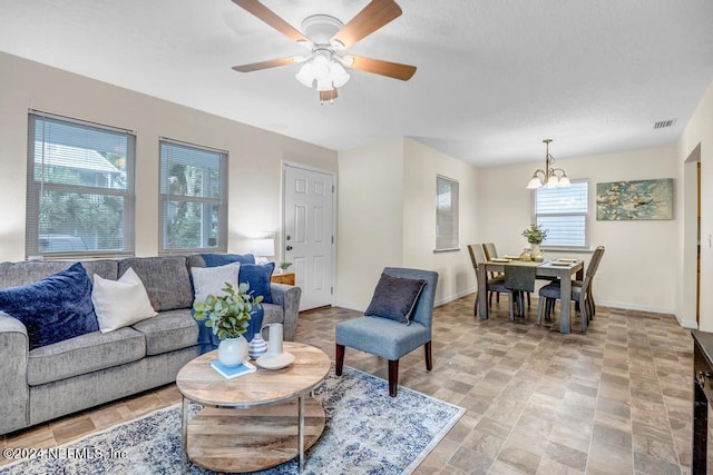 living room featuring a healthy amount of sunlight and ceiling fan with notable chandelier