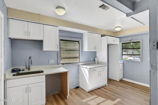 kitchen with sink, light hardwood / wood-style floors, and white cabinetry