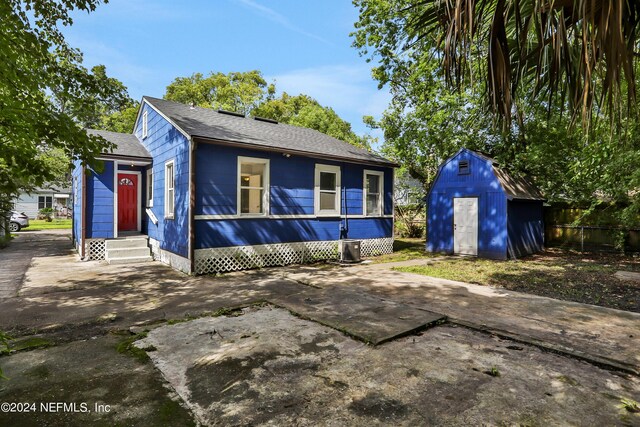 view of front of home featuring cooling unit and a storage shed