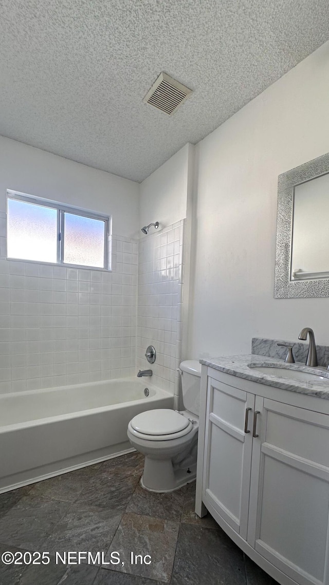 full bathroom featuring vanity, toilet, tiled shower / bath, and a textured ceiling