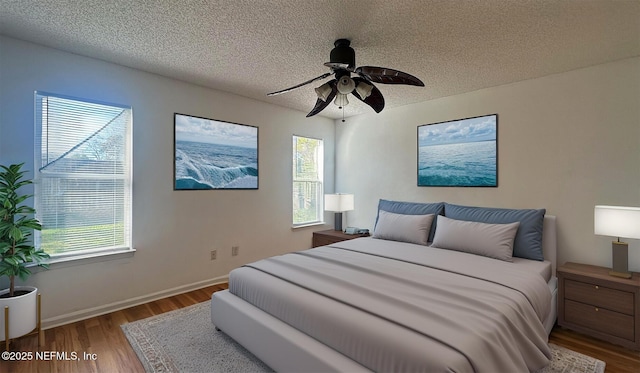 bedroom featuring hardwood / wood-style flooring, a textured ceiling, and ceiling fan