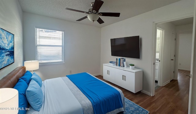 bedroom with ceiling fan, dark wood-type flooring, and a textured ceiling