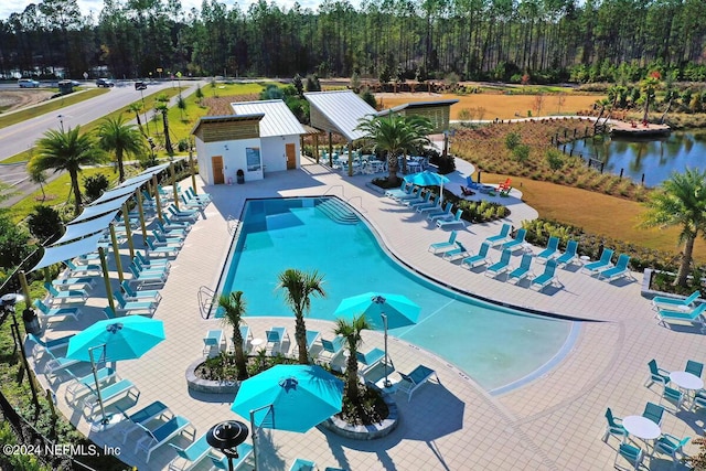 pool featuring a patio area, a water view, and fence