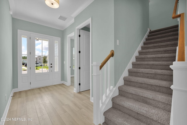 foyer entrance featuring baseboards, visible vents, light wood finished floors, and stairs