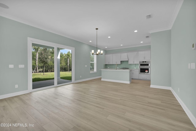 unfurnished living room featuring light wood-type flooring, visible vents, a notable chandelier, and ornamental molding