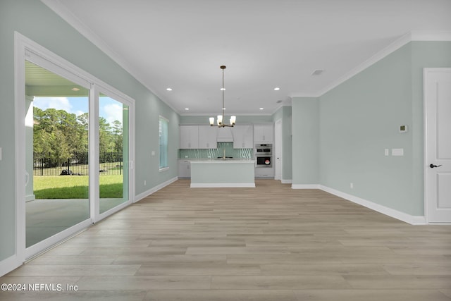 unfurnished living room with recessed lighting, a notable chandelier, baseboards, light wood-type flooring, and crown molding