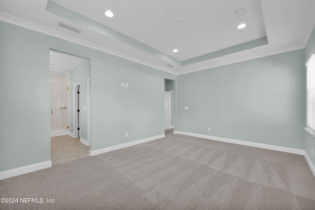 empty room with carpet, a raised ceiling, visible vents, and baseboards