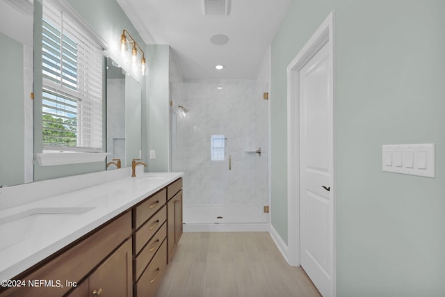 bathroom with wood finished floors, a sink, visible vents, double vanity, and a stall shower