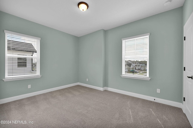 carpeted spare room featuring baseboards