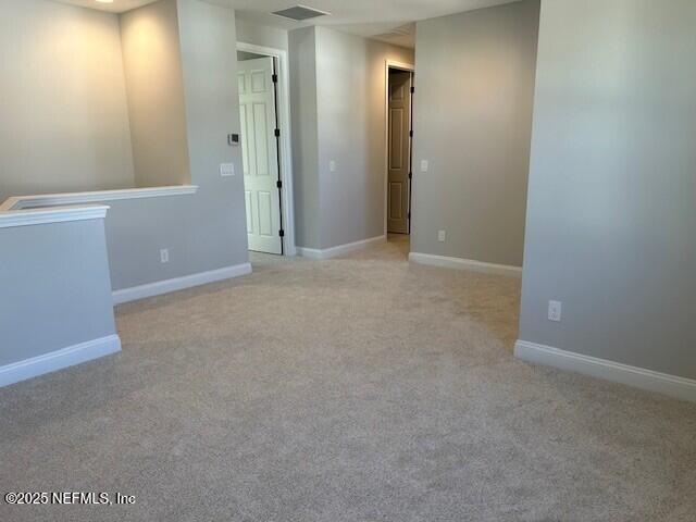 carpeted spare room with visible vents and baseboards