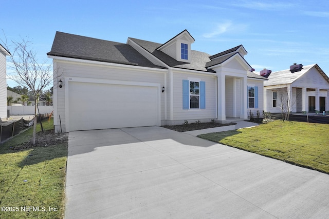 view of front of home with a garage, driveway, a shingled roof, fence, and a front yard