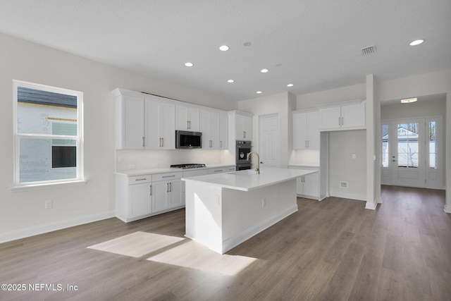 kitchen featuring light hardwood / wood-style flooring, a center island with sink, white cabinets, and gas cooktop