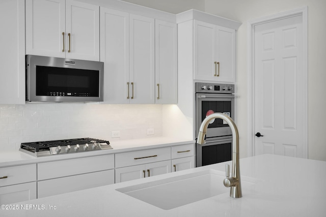 kitchen with sink, decorative backsplash, stainless steel appliances, and white cabinets