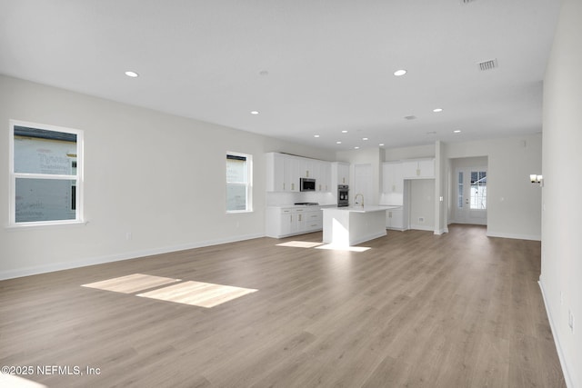 unfurnished living room with sink and light hardwood / wood-style floors